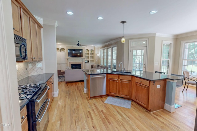 4 Springtree Cir, Durham, NC 27712 - kitchen with appliances with stainless steel finishes, a ceiling fan, crown molding, a glass covered fireplace, and open floor plan