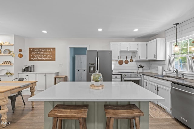 1604 Farm Lake Dr, Holly Springs, NC 27540 - kitchen featuring appliances with stainless steel finishes, a breakfast bar, pendant lighting, white cabinets, and wood finished floors
