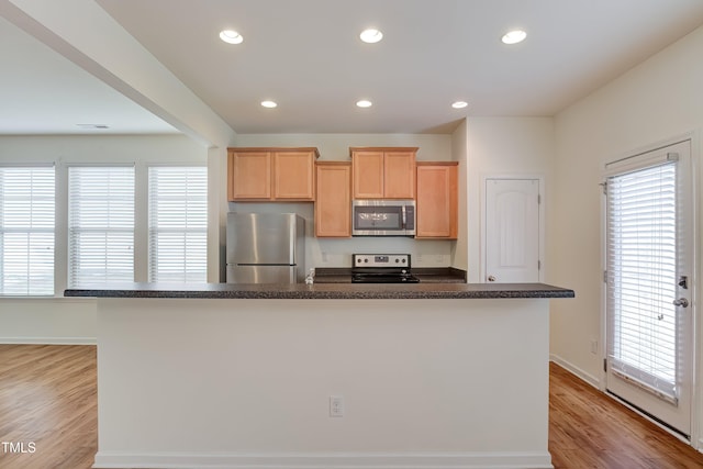 1301 Garden Stone Dr, Raleigh, NC 27610 - kitchen with appliances with stainless steel finishes, dark countertops, light brown cabinetry, light wood-style floors, and recessed lighting