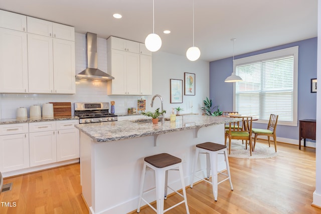 119 W Piedmont Ave, Durham, NC 27707 - kitchen featuring wall chimney exhaust hood, stainless steel range, light wood-type flooring, backsplash, and recessed lighting