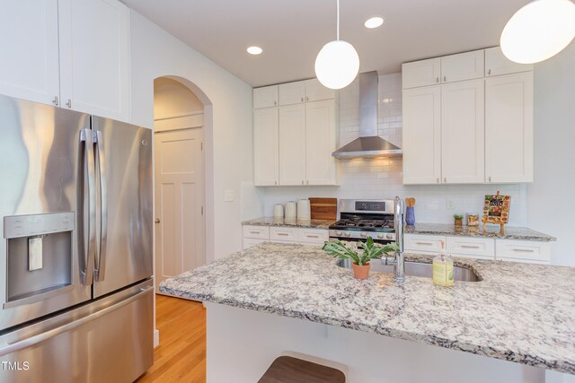 119 W Piedmont Ave, Durham, NC 27707 - kitchen featuring appliances with stainless steel finishes, wall chimney range hood, arched walkways, pendant lighting, and white cabinetry