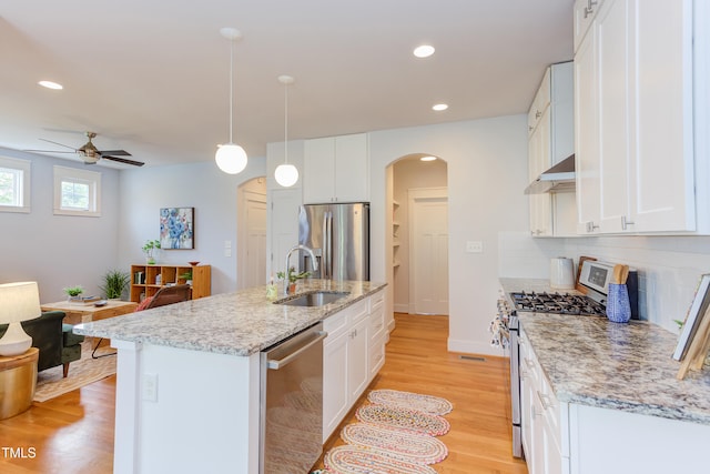 119 W Piedmont Ave, Durham, NC 27707 - kitchen with stainless steel appliances, arched walkways, a ceiling fan, tasteful backsplash, and light wood-type flooring