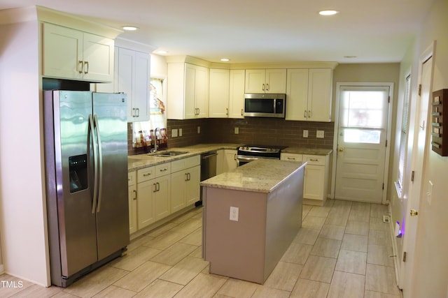 311 Ebon Rd, Durham, NC 27713 - kitchen with stainless steel appliances, decorative backsplash, light stone countertops, a kitchen island, and white cabinetry