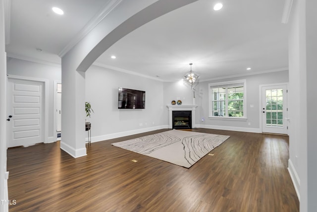 425 Cahors Trl, Holly Springs, NC 27540 - unfurnished living room featuring dark wood-style floors, recessed lighting, ornamental molding, arched walkways, and a fireplace with flush hearth