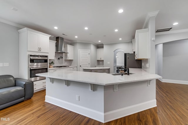 425 Cahors Trl, Holly Springs, NC 27540 - kitchen with wall chimney range hood, double oven, crown molding, refrigerator, and a peninsula