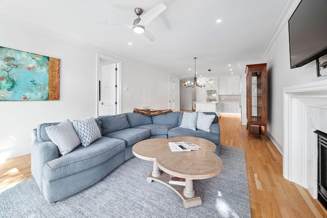781 Crabtree Crossing Pkwy, Cary, NC 27513 - living room featuring ornamental molding, a high end fireplace, light wood-style floors, a chandelier, and a ceiling fan