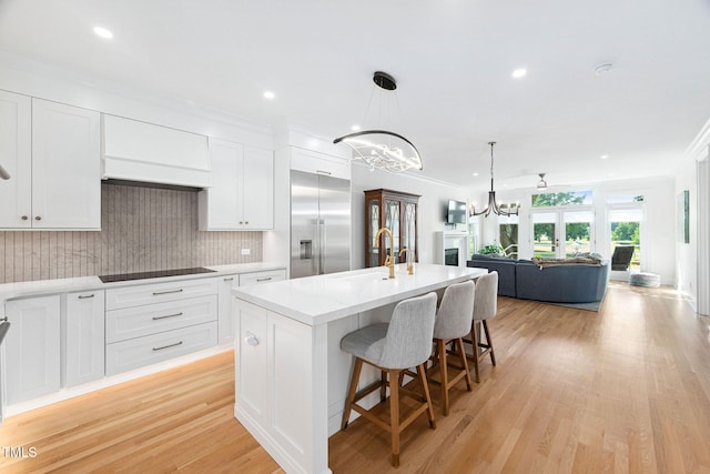 781 Crabtree Crossing Pkwy, Cary, NC 27513 - kitchen with stainless steel built in refrigerator, a chandelier, black electric cooktop, open floor plan, and white cabinets
