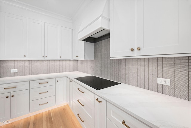 781 Crabtree Crossing Pkwy, Cary, NC 27513 - kitchen with black electric cooktop, crown molding, custom exhaust hood, white cabinetry, and light stone counters