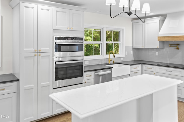 310 E Pilot St, Durham, NC 27707 - kitchen with appliances with stainless steel finishes, custom exhaust hood, wood finished floors, and tasteful backsplash