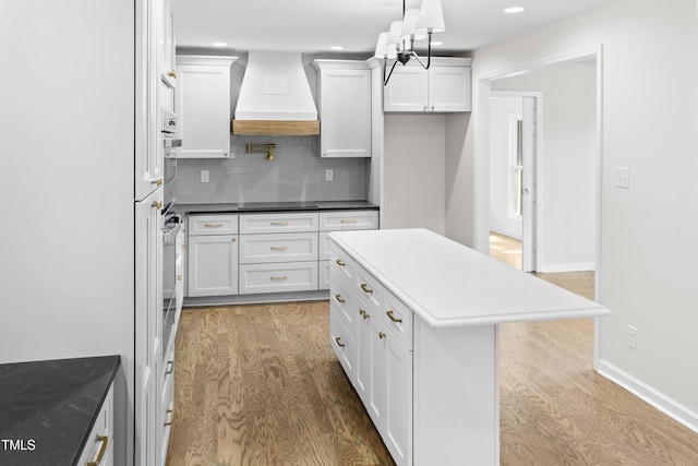 310 E Pilot St, Durham, NC 27707 - kitchen featuring custom exhaust hood, wood finished floors, black electric cooktop, white cabinets, and recessed lighting