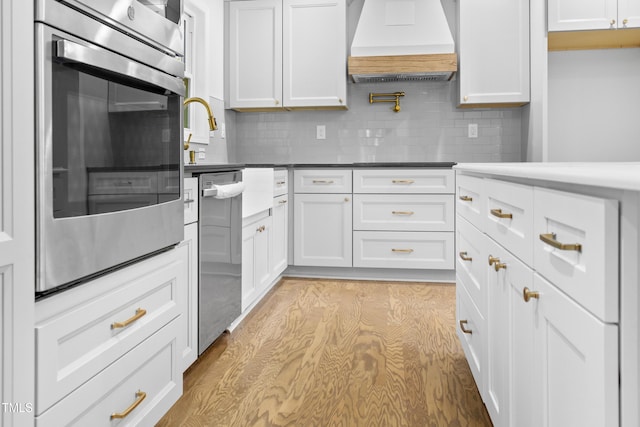 310 E Pilot St, Durham, NC 27707 - kitchen featuring premium range hood, appliances with stainless steel finishes, decorative backsplash, and white cabinetry