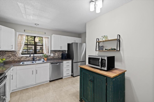 18 Willow Bridge Dr, Durham, NC 27707 - kitchen featuring appliances with stainless steel finishes, backsplash, a textured ceiling, white cabinetry, and decorative light fixtures
