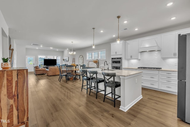 115 Circle City Way, Pittsboro, NC 27312 - kitchen with recessed lighting, custom range hood, white cabinetry, an island with sink, and backsplash