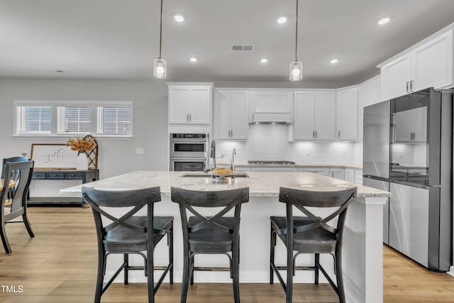 115 Circle City Way, Pittsboro, NC 27312 - kitchen with stainless steel appliances, custom exhaust hood, tasteful backsplash, light stone counters, and a kitchen island with sink