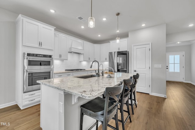 115 Circle City Way, Pittsboro, NC 27312 - kitchen featuring stainless steel appliances, light wood-style floors, light stone counters, white cabinetry, and recessed lighting
