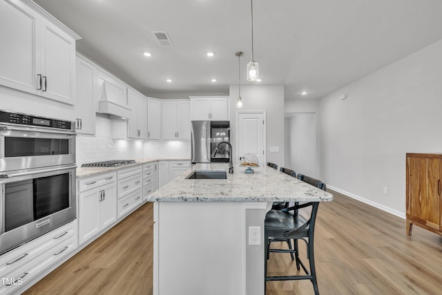 115 Circle City Way, Pittsboro, NC 27312 - kitchen featuring appliances with stainless steel finishes, a kitchen bar, light wood-style floors, white cabinetry, and recessed lighting