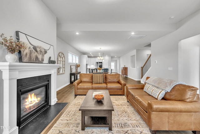 115 Circle City Way, Pittsboro, NC 27312 - living room featuring light wood-style flooring, a glass covered fireplace, stairway, recessed lighting, and a chandelier