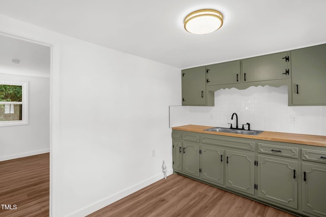 1907 Wilkins St, Burlington, NC 27217 - kitchen with green cabinetry, light wood finished floors, and decorative backsplash