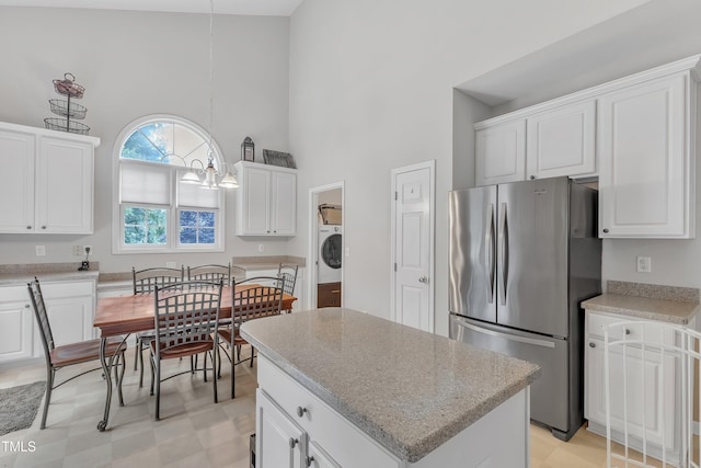 13201 Townfield Dr, Raleigh, NC 27614 - kitchen featuring freestanding refrigerator, washer / clothes dryer, a high ceiling, white cabinets, and a kitchen island