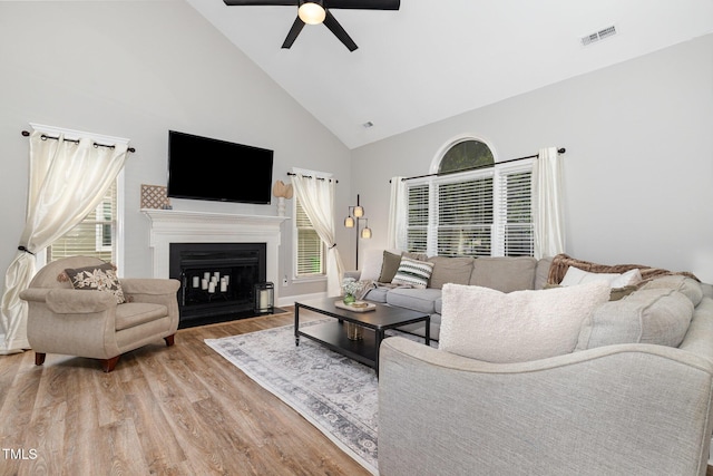 5609 Edgebury Rd, Raleigh, NC 27613 - living room featuring high vaulted ceiling, ceiling fan, wood finished floors, and a fireplace with flush hearth