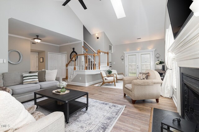 5609 Edgebury Rd, Raleigh, NC 27613 - living area with high vaulted ceiling, stairway, a fireplace, ceiling fan, and a skylight