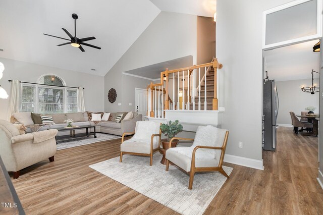 5609 Edgebury Rd, Raleigh, NC 27613 - living room with a chandelier, stairway, ceiling fan, high vaulted ceiling, and wood finished floors