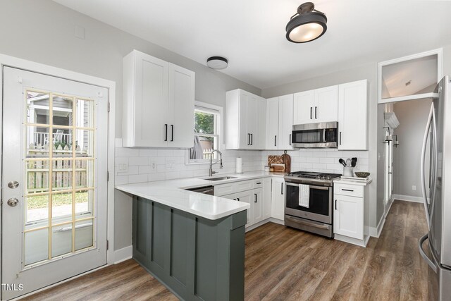5609 Edgebury Rd, Raleigh, NC 27613 - kitchen featuring appliances with stainless steel finishes, a peninsula, backsplash, dark wood-style flooring, and white cabinetry