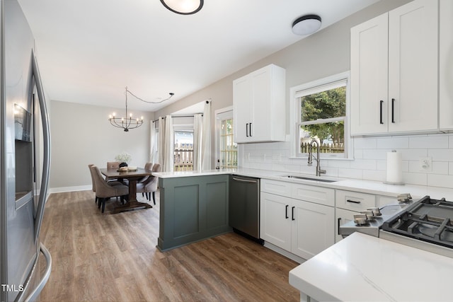 5609 Edgebury Rd, Raleigh, NC 27613 - kitchen with appliances with stainless steel finishes, a chandelier, wood finished floors, and backsplash