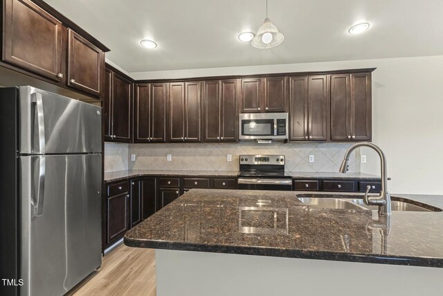 245 E Webber Ln, Clayton, NC 27527 - kitchen with stainless steel appliances, dark brown cabinets, pendant lighting, light wood-type flooring, and dark stone countertops