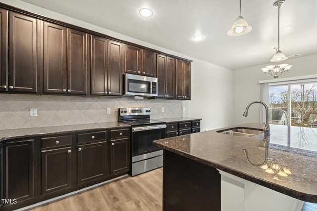 245 E Webber Ln, Clayton, NC 27527 - kitchen featuring appliances with stainless steel finishes, a chandelier, decorative backsplash, pendant lighting, and light wood-style flooring