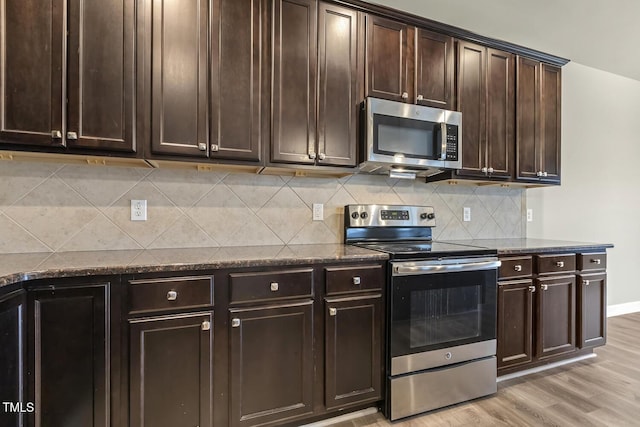 245 E Webber Ln, Clayton, NC 27527 - kitchen featuring stainless steel appliances, dark stone counters, light wood-style flooring, decorative backsplash, and dark brown cabinets
