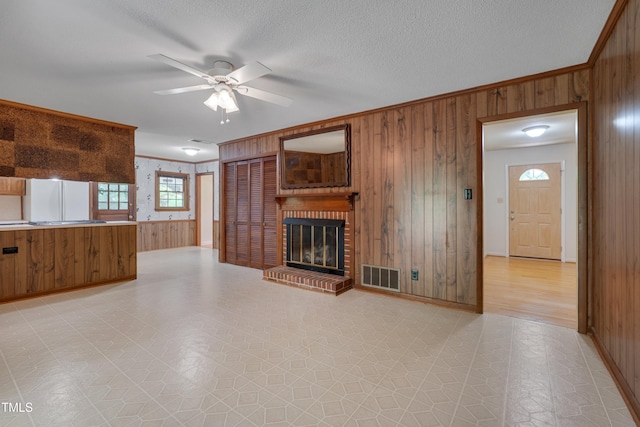 906 Cindy St, Cary, NC 27511 - unfurnished living room featuring wooden walls, ceiling fan, a fireplace, crown molding, and light floors