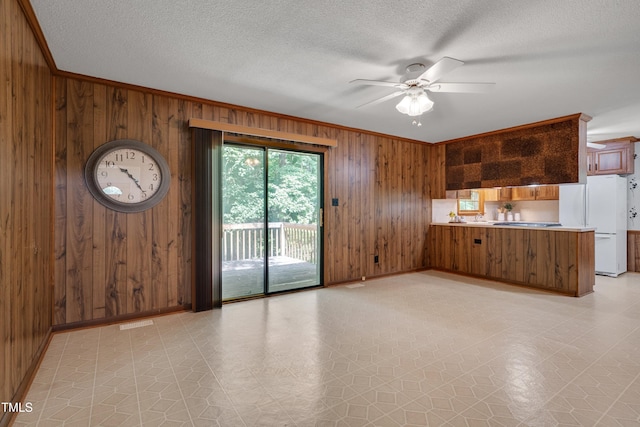 906 Cindy St, Cary, NC 27511 - unfurnished living room featuring wooden walls, crown molding, light floors, a ceiling fan, and a textured ceiling