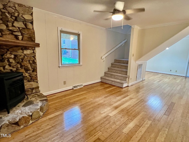 612 Williamsboro St, Oxford, NC 27565 - unfurnished living room with crown molding, a wood stove, stairs, wood-type flooring, and a ceiling fan