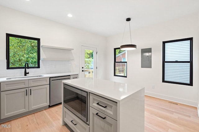 2205 Tampa Ave, Durham, NC 27705 - kitchen with appliances with stainless steel finishes, light wood finished floors, electric panel, decorative backsplash, and light countertops
