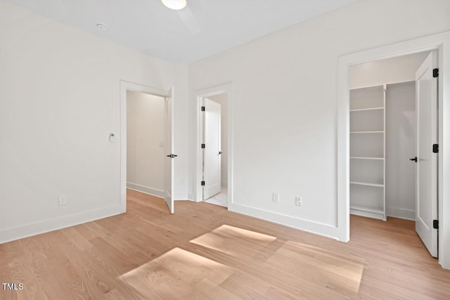 2205 Tampa Ave, Durham, NC 27705 - unfurnished bedroom with a walk in closet, wood finished floors, a closet, and ceiling fan