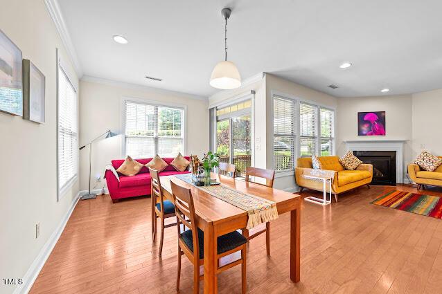 4007 Strendal Dr, Cary, NC 27519 - dining area featuring a glass covered fireplace, ornamental molding, wood finished floors, and recessed lighting