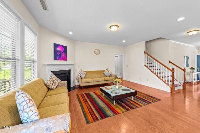 4007 Strendal Dr, Cary, NC 27519 - living area featuring wood finished floors, stairway, a fireplace with flush hearth, and recessed lighting