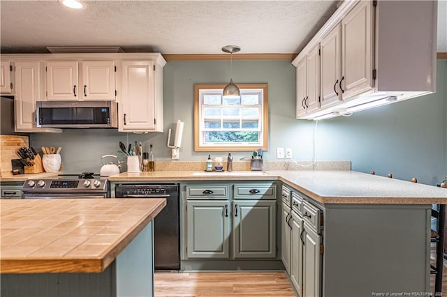 1360 Rays Bridge Rd, Whispering Pines, NC 28327 - kitchen with appliances with stainless steel finishes, a textured ceiling, light wood-style flooring, white cabinetry, and hanging light fixtures