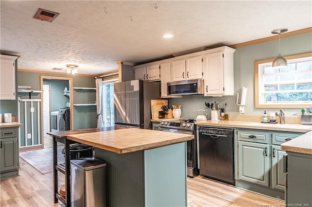 1360 Rays Bridge Rd, Whispering Pines, NC 28327 - kitchen featuring appliances with stainless steel finishes, washing machine and clothes dryer, crown molding, butcher block counters, and light wood finished floors