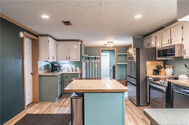 1360 Rays Bridge Rd, Whispering Pines, NC 28327 - kitchen with stainless steel appliances, ornamental molding, light wood finished floors, a textured ceiling, and a center island