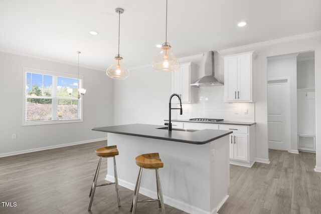 1409 Jasmine View Way, Knightdale, NC 27545 - kitchen featuring wall chimney range hood, ornamental molding, decorative backsplash, an island with sink, and light wood-style floors