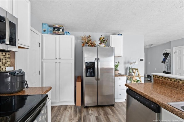 4450 Chesterbrook Dr, Fayetteville, NC 28314 - kitchen with appliances with stainless steel finishes, a textured ceiling, white cabinets, light wood finished floors, and decorative backsplash