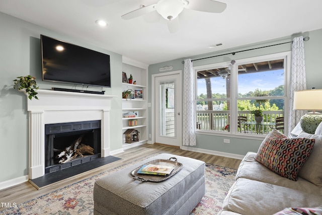 720 Springfork Dr, Cary, NC 27513 - living room featuring wood finished floors, ceiling fan, a fireplace, built in features, and recessed lighting