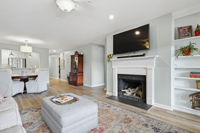 720 Springfork Dr, Cary, NC 27513 - living room with light wood-style floors, a ceiling fan, a fireplace with raised hearth, built in features, and recessed lighting