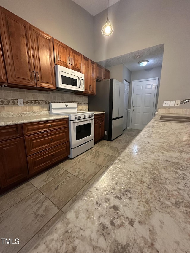 216 Parrish Farm Ln, Benson, NC 27504 - kitchen with white appliances, decorative backsplash, light countertops, brown cabinetry, and pendant lighting