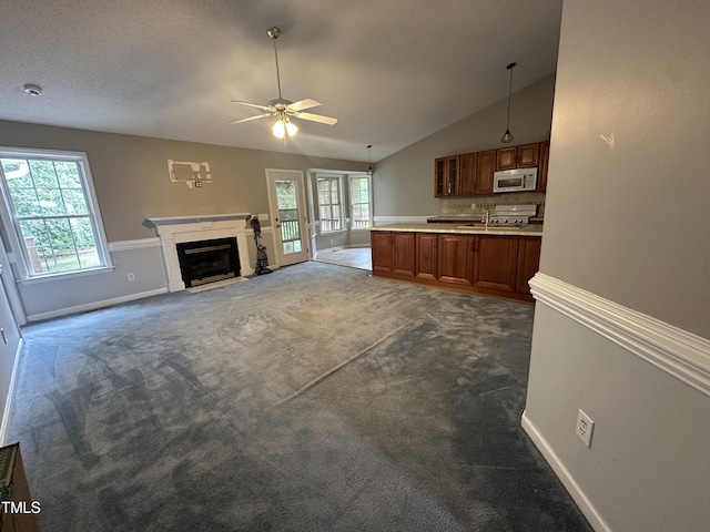 216 Parrish Farm Ln, Benson, NC 27504 - unfurnished living room featuring ceiling fan, healthy amount of natural light, dark carpet, vaulted ceiling, and a fireplace with flush hearth