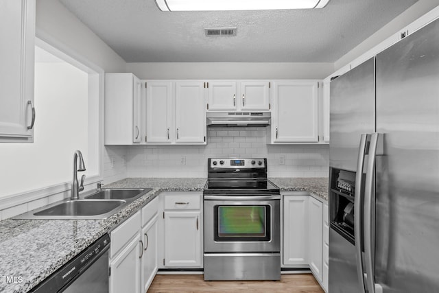 82 Forest Oaks Dr, Durham, NC 27705 - kitchen with appliances with stainless steel finishes, under cabinet range hood, white cabinets, a textured ceiling, and light wood-style flooring