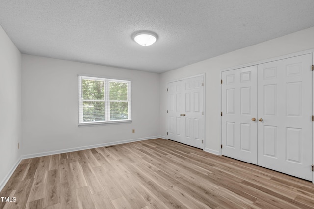 82 Forest Oaks Dr, Durham, NC 27705 - unfurnished bedroom with multiple closets, light wood-type flooring, and a textured ceiling