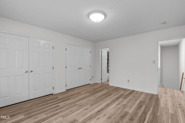 82 Forest Oaks Dr, Durham, NC 27705 - unfurnished bedroom with multiple closets, light wood-style flooring, and a textured ceiling